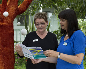 Two nurses standing in the garden looking at the pamphlet. 