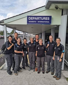 A group of volunteers outside the departures terminal at a small airport. 