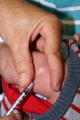 Image of an infant's arm and a health care worker administering a vaccine.