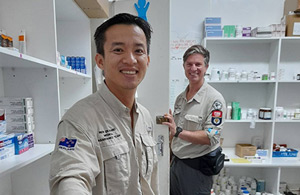 Two volunteers in a room with pharmaceutical supplies. 