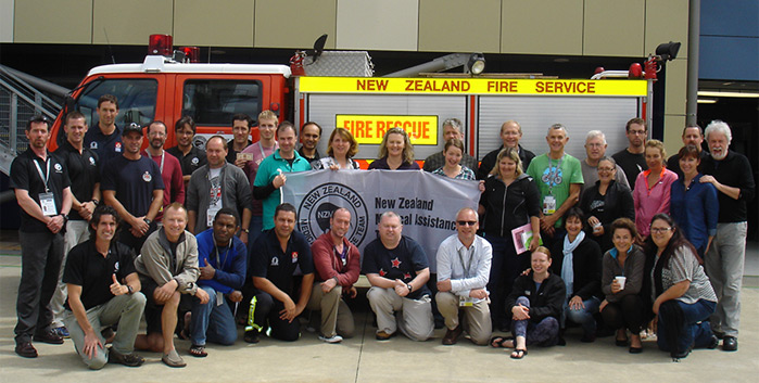 NZMAT volunteers gathered together in front of a fire engine. 