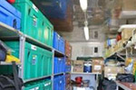 Photo of a long narrow room, piled with supply boxes.