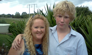 Photo of a teenage boy standing with his arm around his mum. 