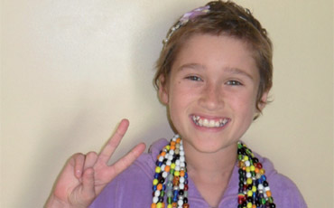 Photo of Kelcey, with a big smile and making the peace symbol. 