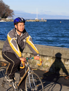 A young man cycling to work along the waterfront. 