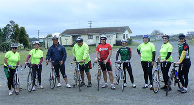 Photo of 9 cyclists posing with their bikes. 