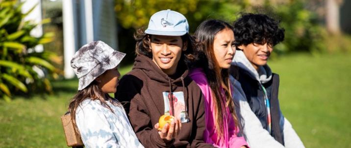 Four rangatahi sharing an orange. 
