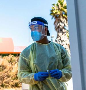 A man in PPE, include face shield, mask, gown and gloves.