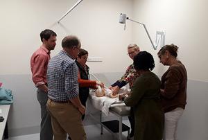 A group of trainees practicing on a dummy baby.