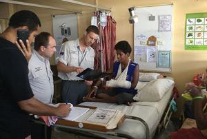 A volunteer speaking to a patient with a bandaged arm.