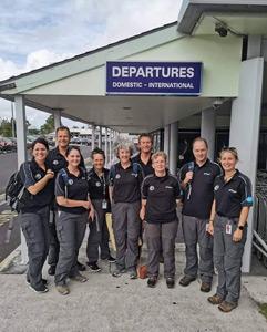 A group of volunteers outside the departures terminal at a small airport.